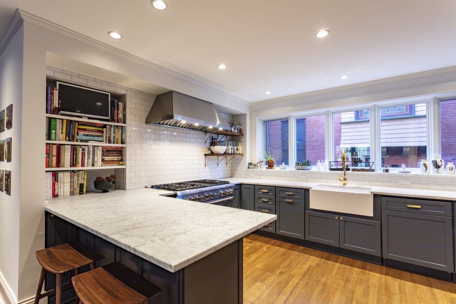 Modern kitchen with large island, dark cabinets, marble countertops, and window above the sink