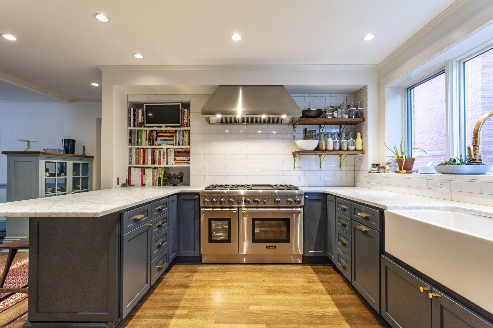 Modern kitchen with dark cabinets, white countertops, stainless range, and large windows