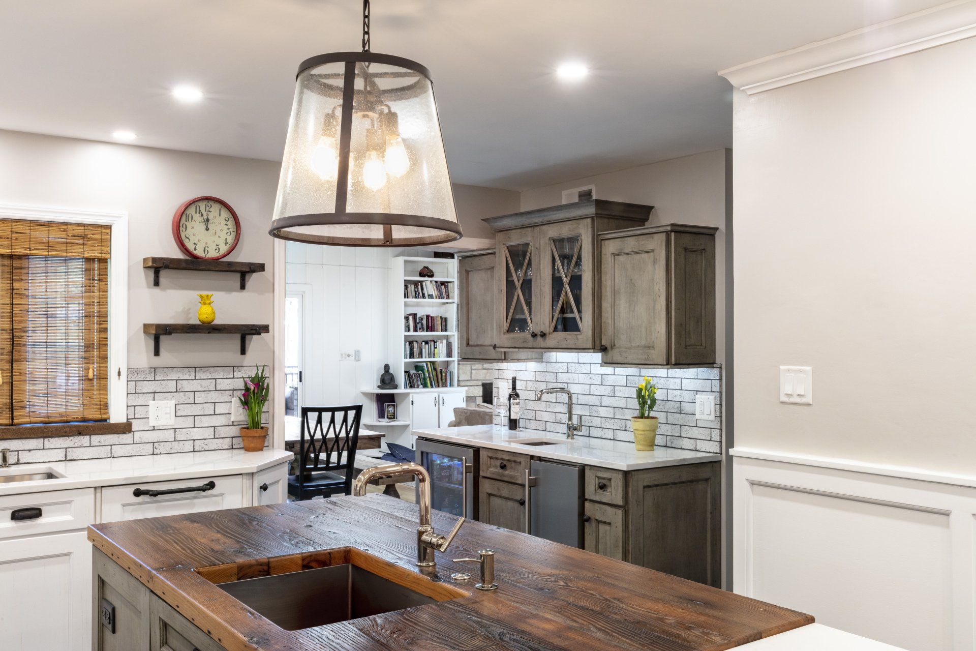 Bright kitchen with island, dark wood cabinets, white tile backsplash, and hanging pendant light
