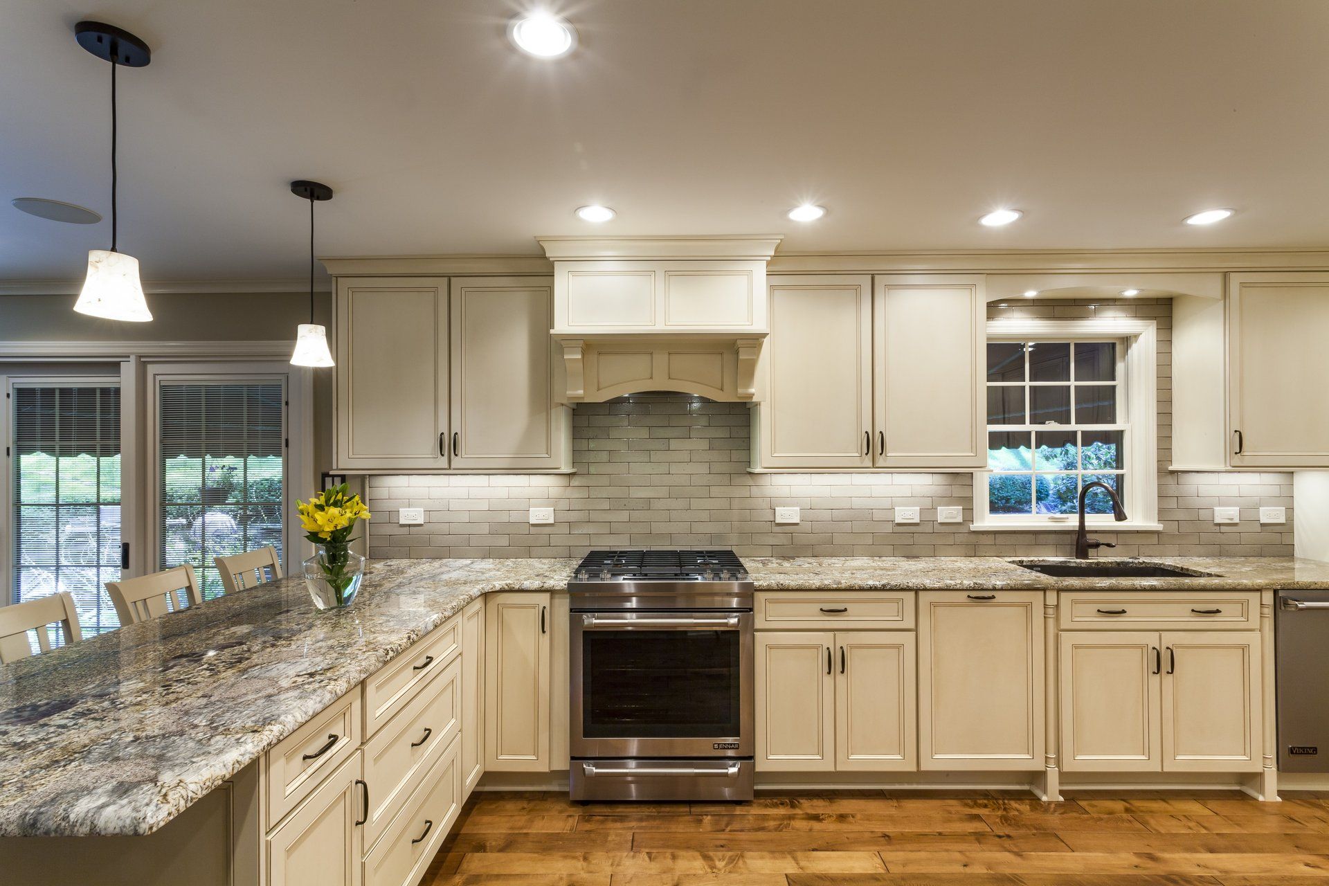 Bright, modern kitchen with white cabinets, granite counters, stainless stove, and pendant lights.