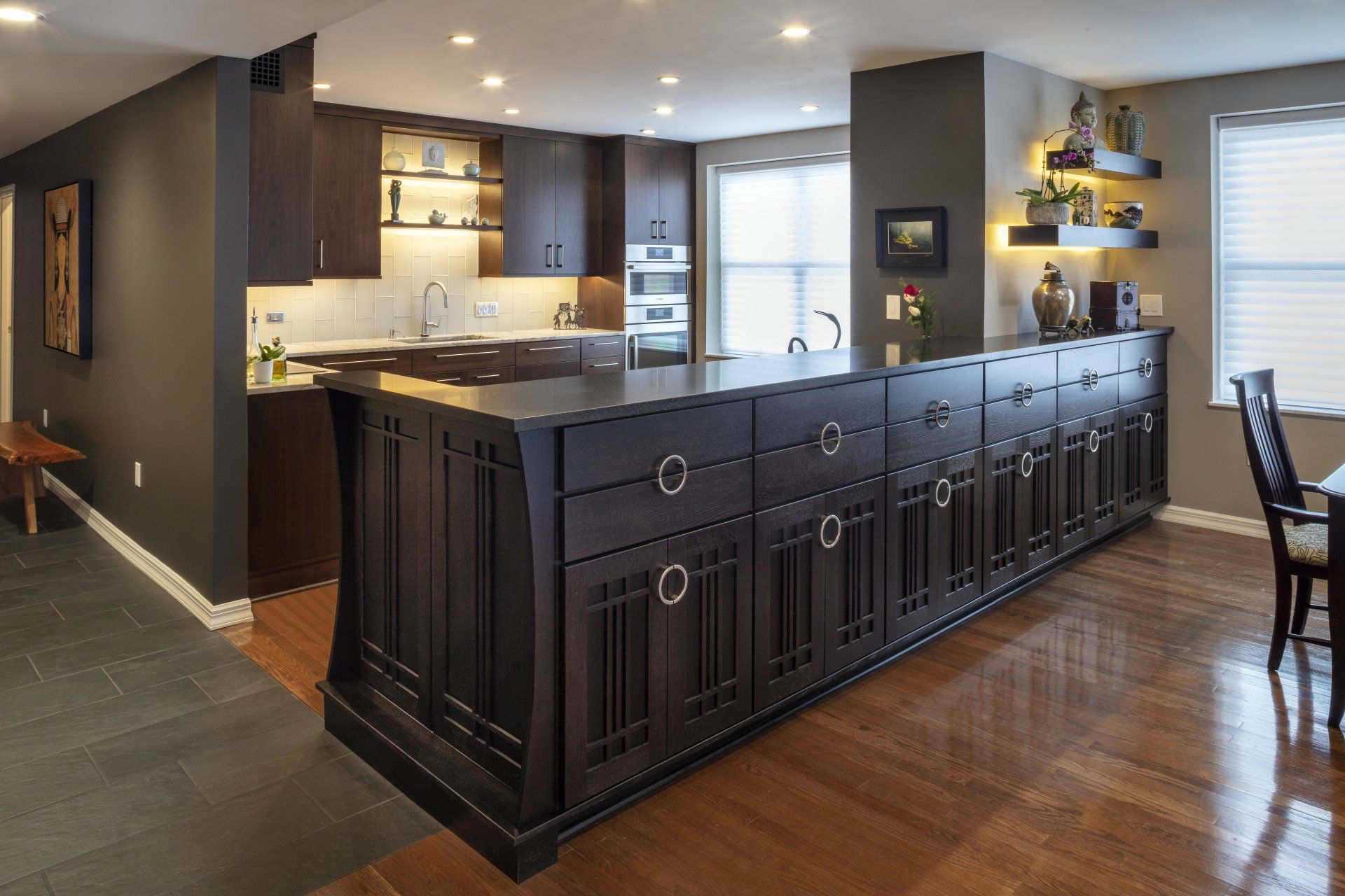 Modern kitchen with dark island cabinetry, wood floors, and stainless steel appliances