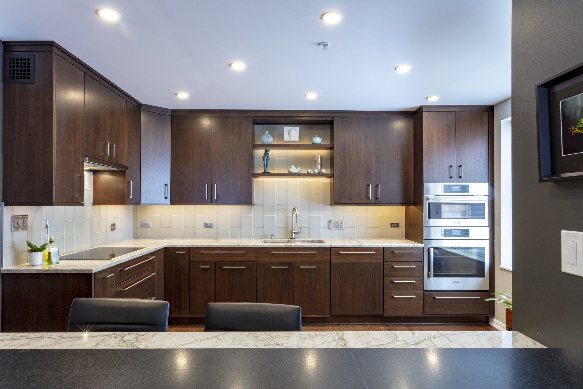 Modern kitchen with dark wood cabinets, stainless appliances, and a white tile backsplash