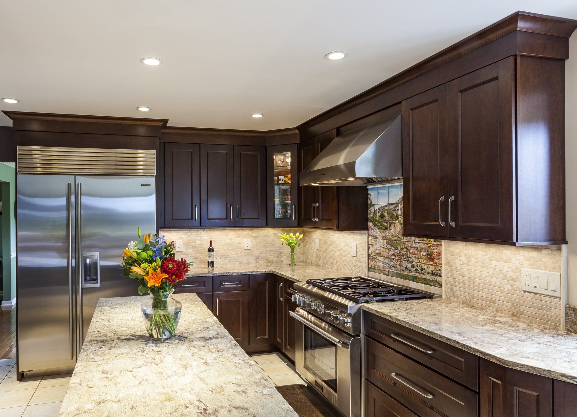Modern kitchen with dark wood cabinets, granite countertops, stainless steel appliances, and a vase of flowers on the island