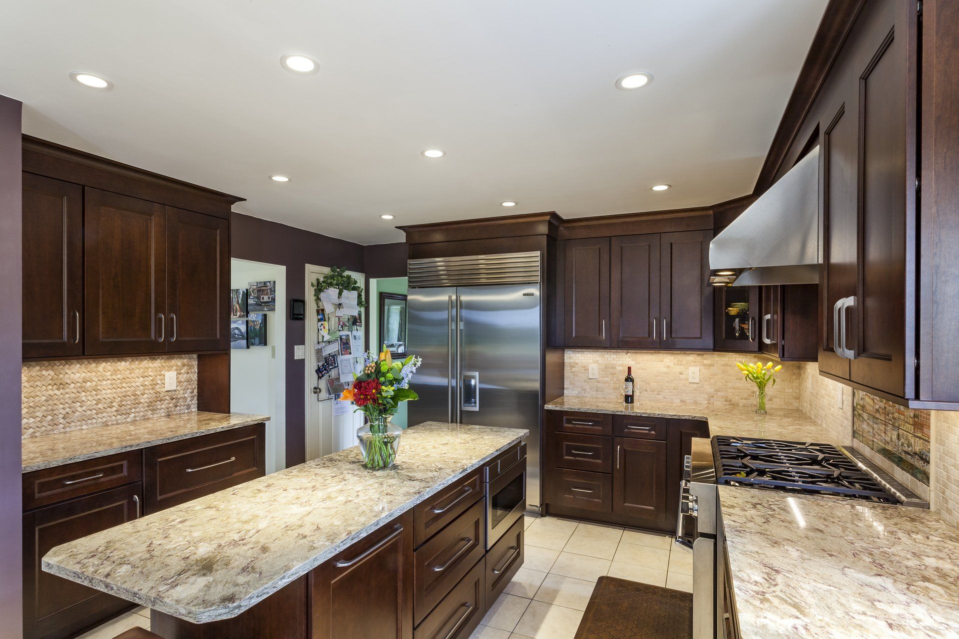 Modern kitchen with dark wood cabinets, granite island, stainless appliances, and recessed lighting