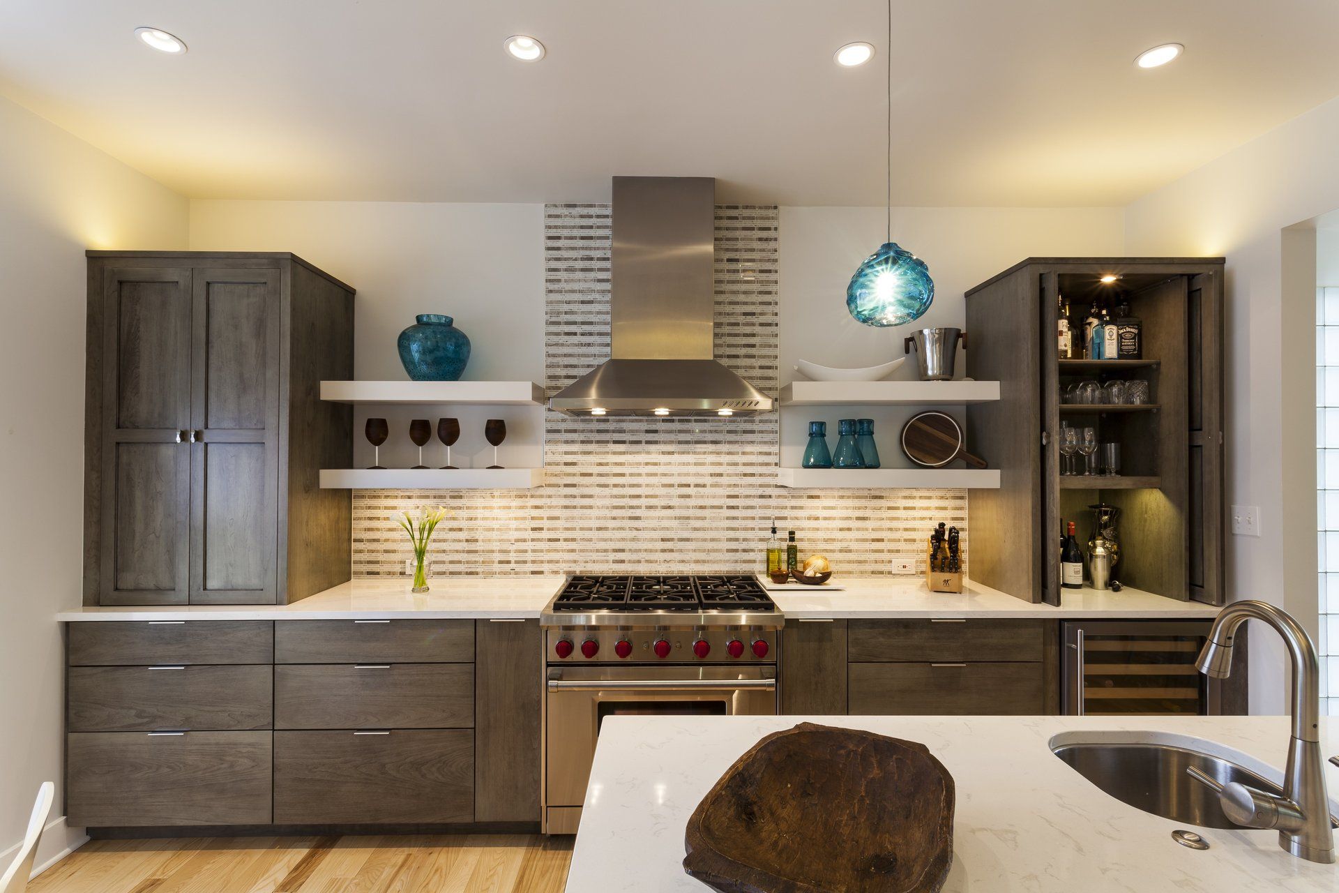 Modern kitchen with gray cabinets, white tile backsplash, stainless range, and pendant lights