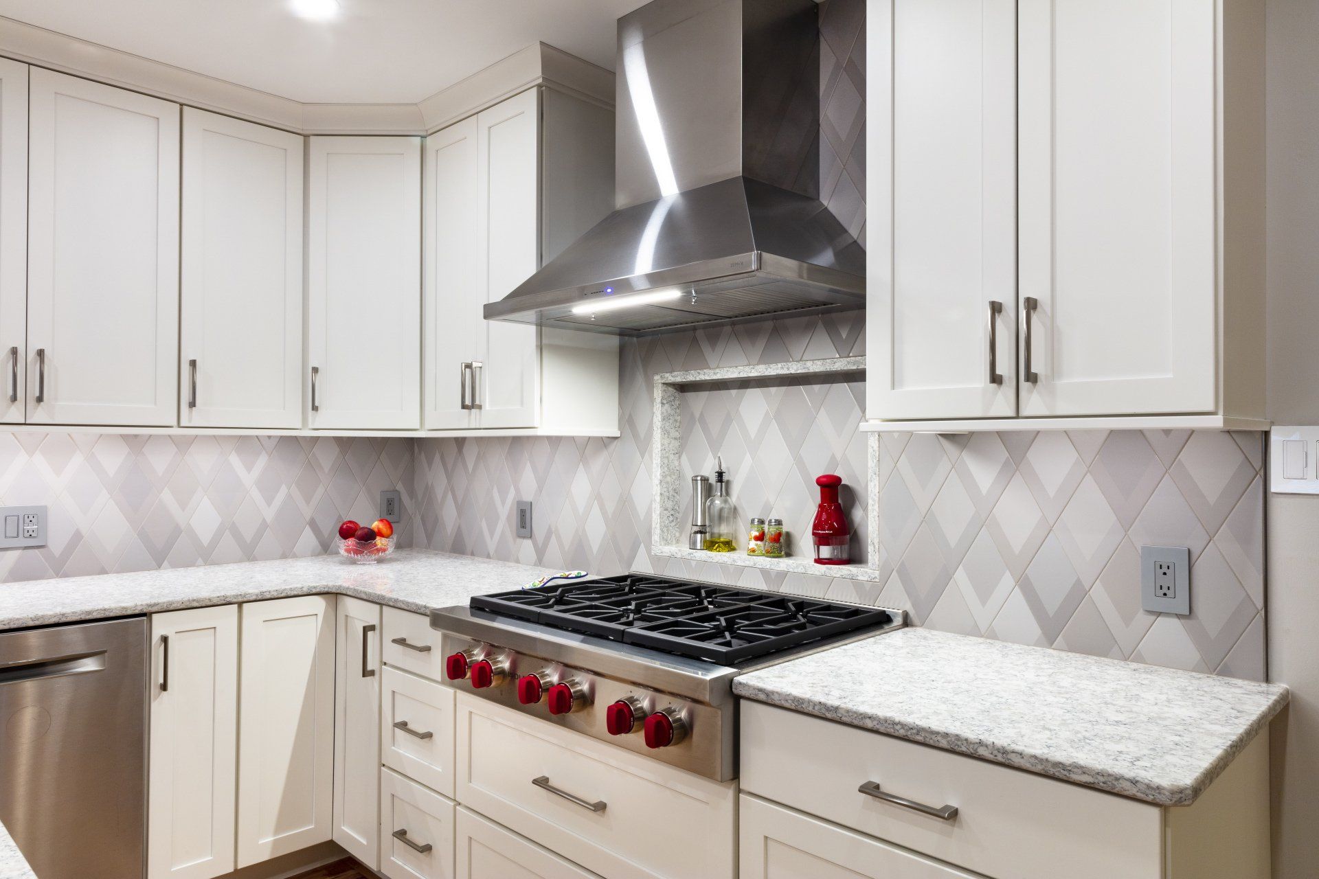 Modern white kitchen with stainless steel range hood, gas stove, and light gray backsplash