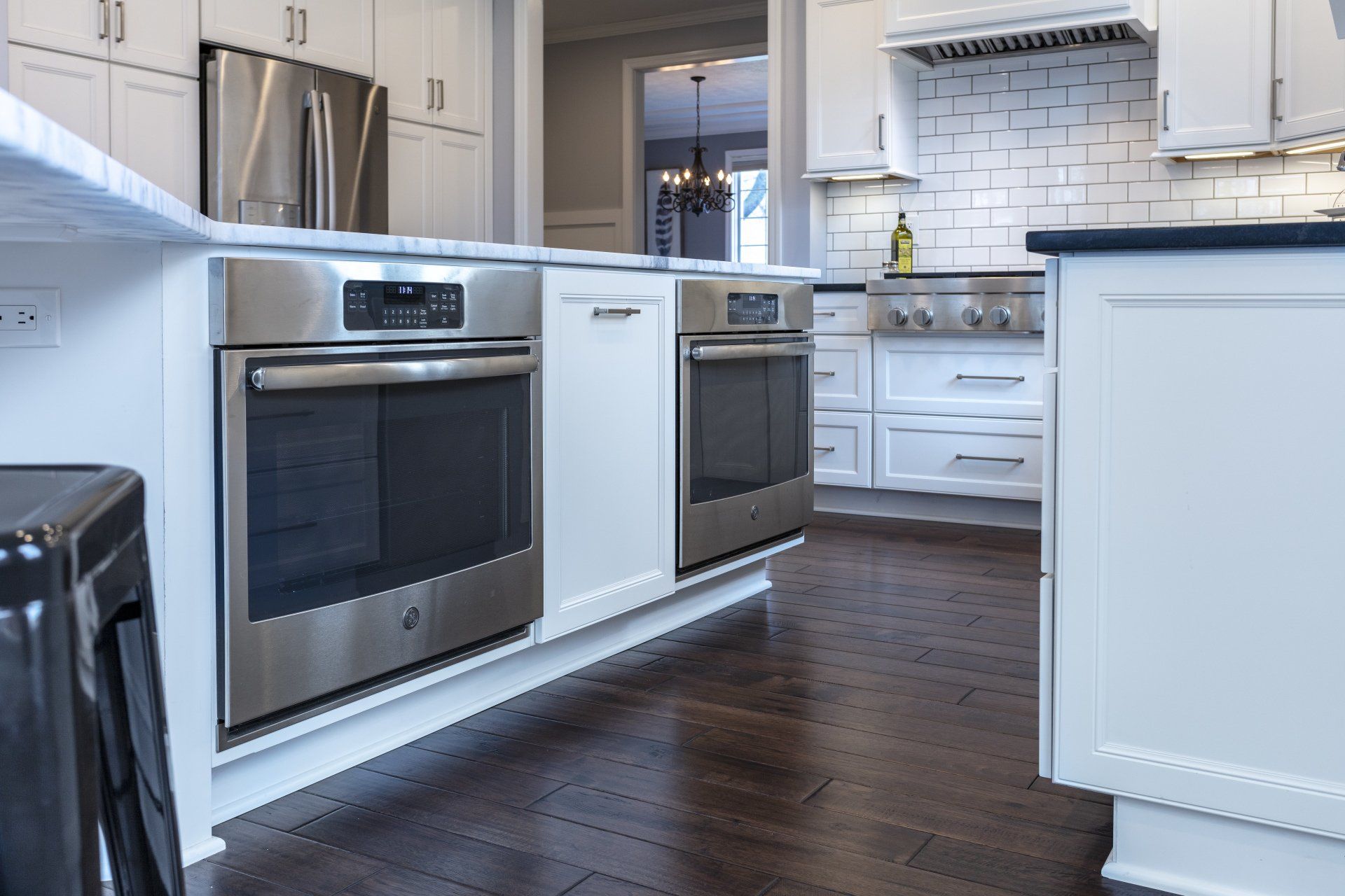 Modern kitchen with stainless steel appliances, white cabinets, and dark hardwood floors