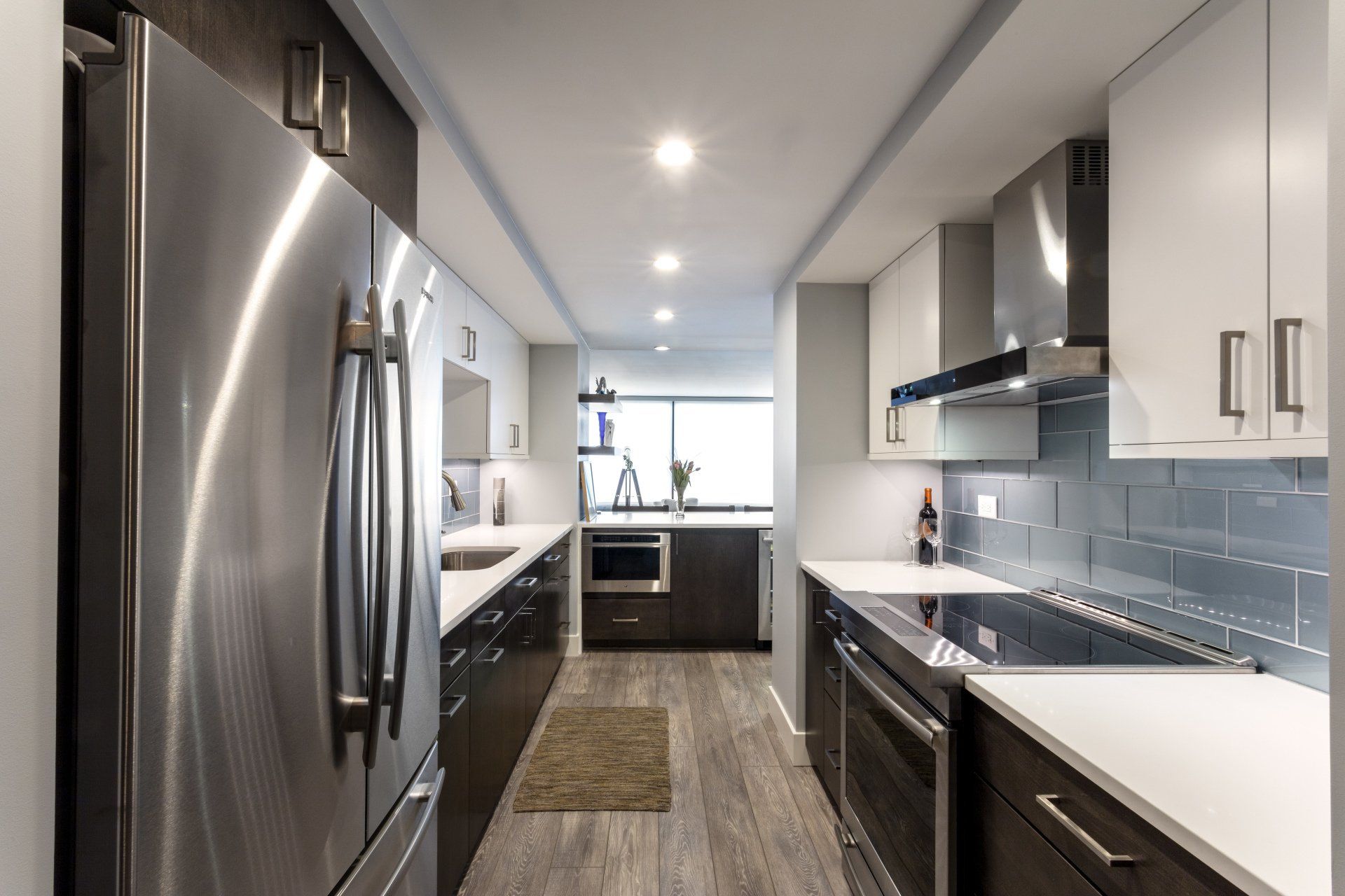 Modern galley kitchen with stainless steel appliances, white cabinets, and gray countertops