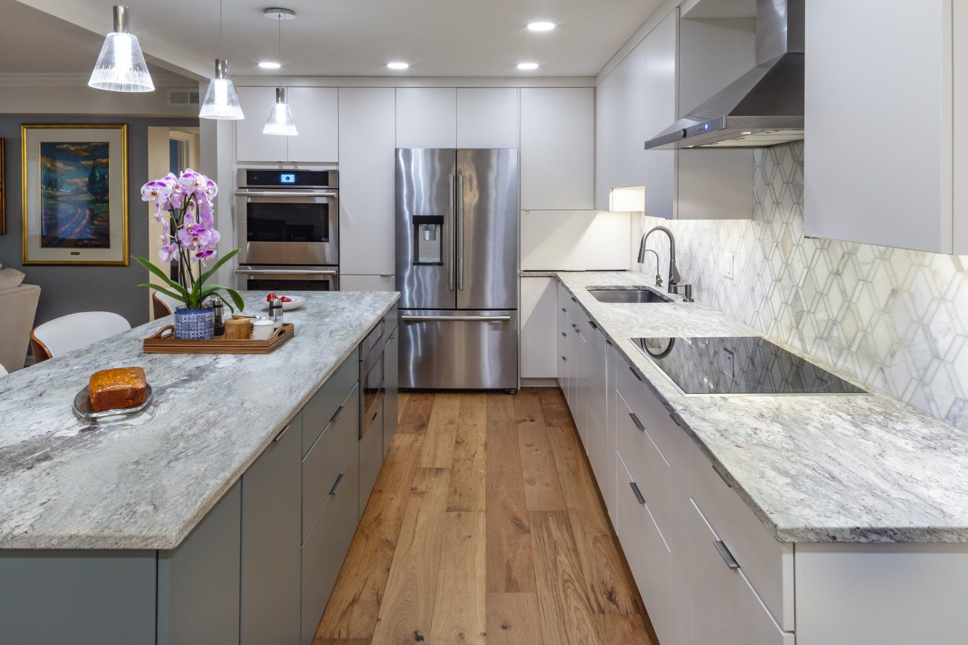 Modern kitchen with granite island, stainless steel appliances, white cabinets, and wood floors