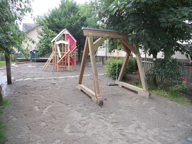 Ein Spielplatz mit Schaukel und einem Haus im Hintergrund