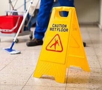 Worker Mopping Floor With Wet Floor Caution Sign — Carpet Cleaning in Pottsville, PA Worker Mopping Floor With Wet Floor Caution Sign — Carpet Cleaning in Pottsville, PA