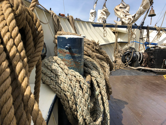Opgerolde scheepstouwen en dekuitrusting op een schip in fel zonlicht.