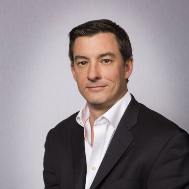 A man in a suit and white shirt is smiling for the camera
