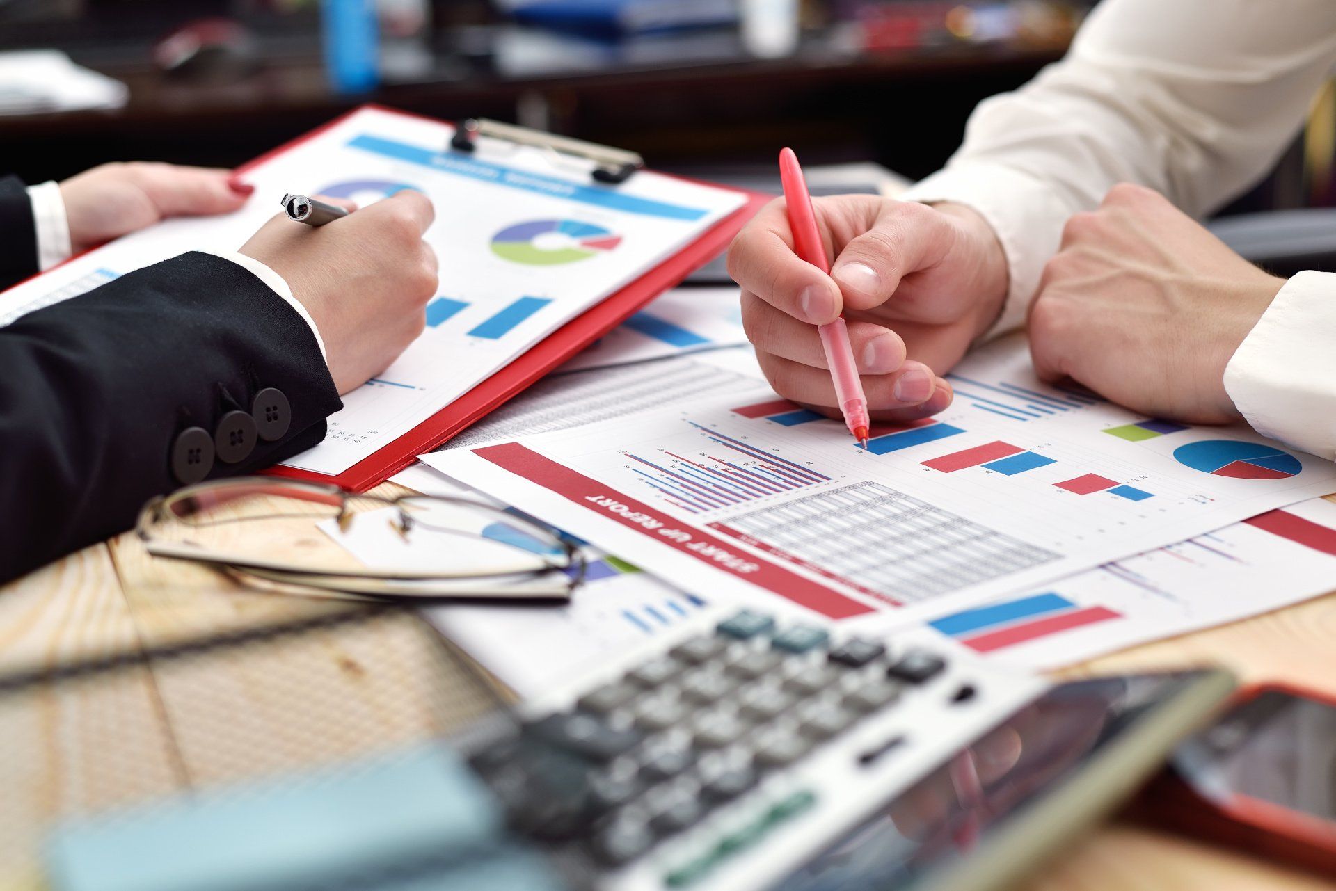 A group of people are sitting at a table with papers and a calculator.
