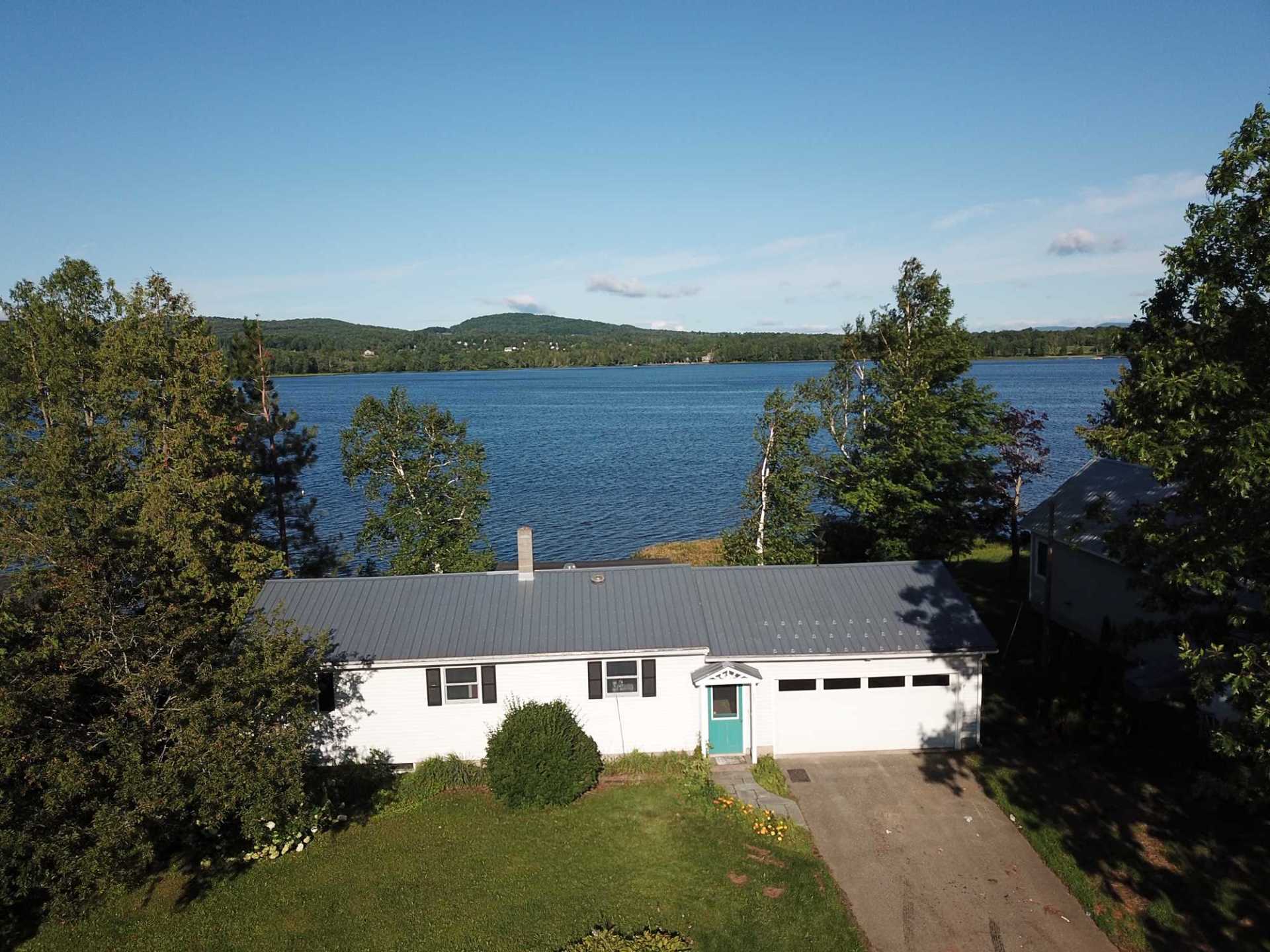 An aerial view of a house with a lake in the background