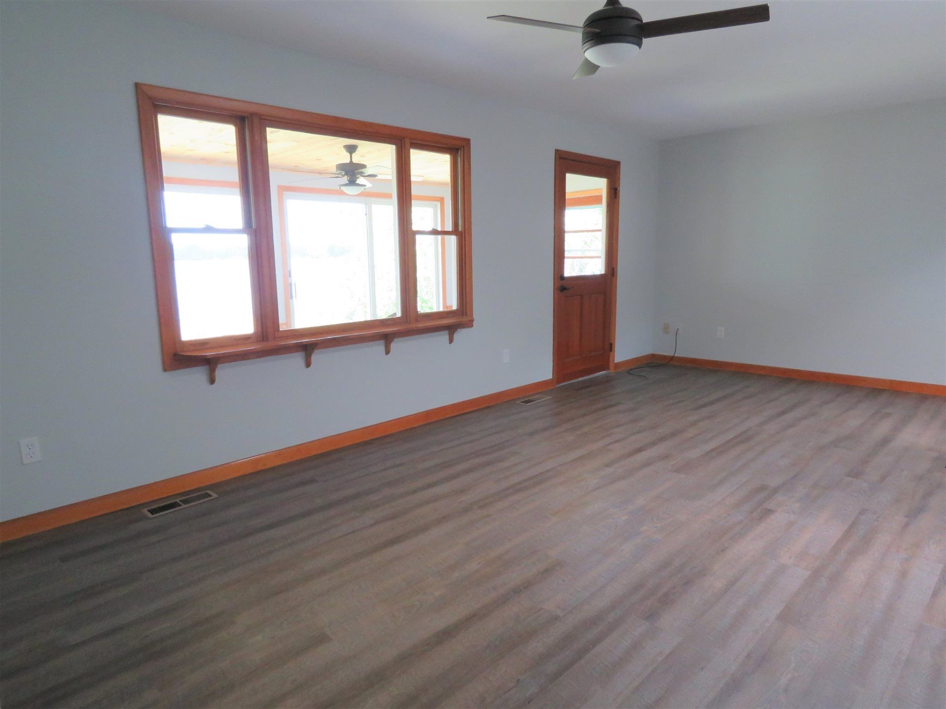 An empty living room with hardwood floors and a ceiling fan