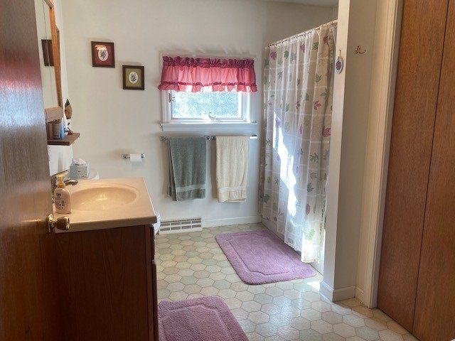 A bathroom with a sink , mirror , and shower curtain.