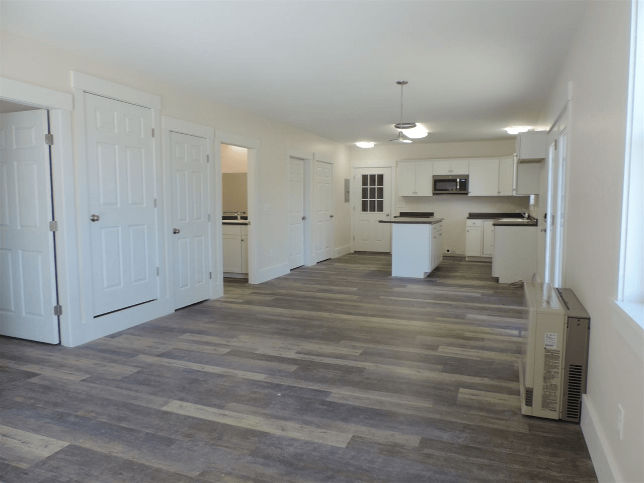 A large empty room with a wooden floor and white cabinets