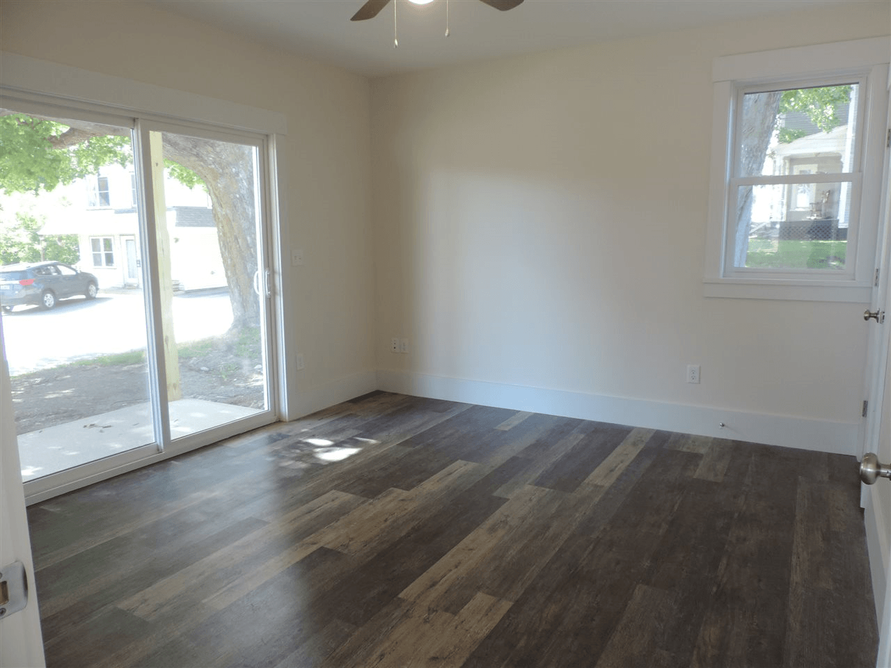 An empty room with sliding glass doors and a ceiling fan