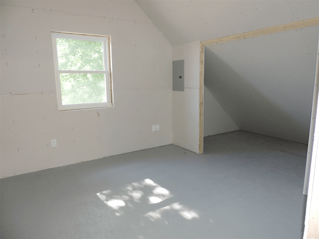 An empty room with a window and a gray floor