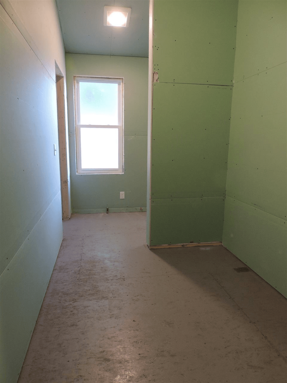 An empty room with green walls and a window