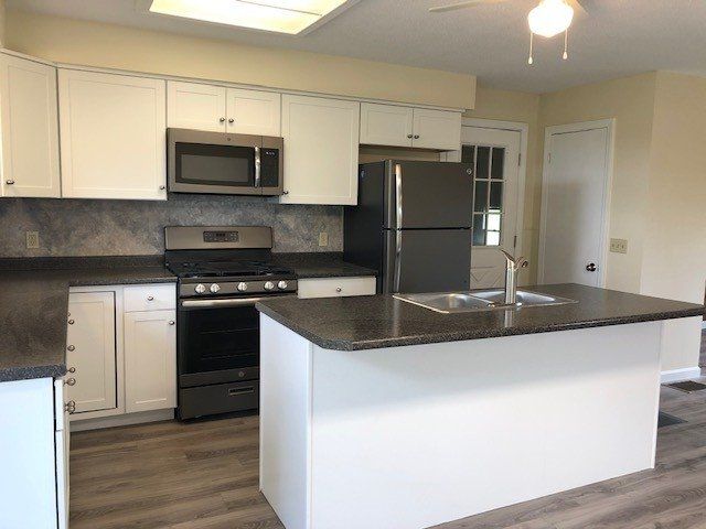 Kitchen with white cabinets, dark countertops, and a large island.