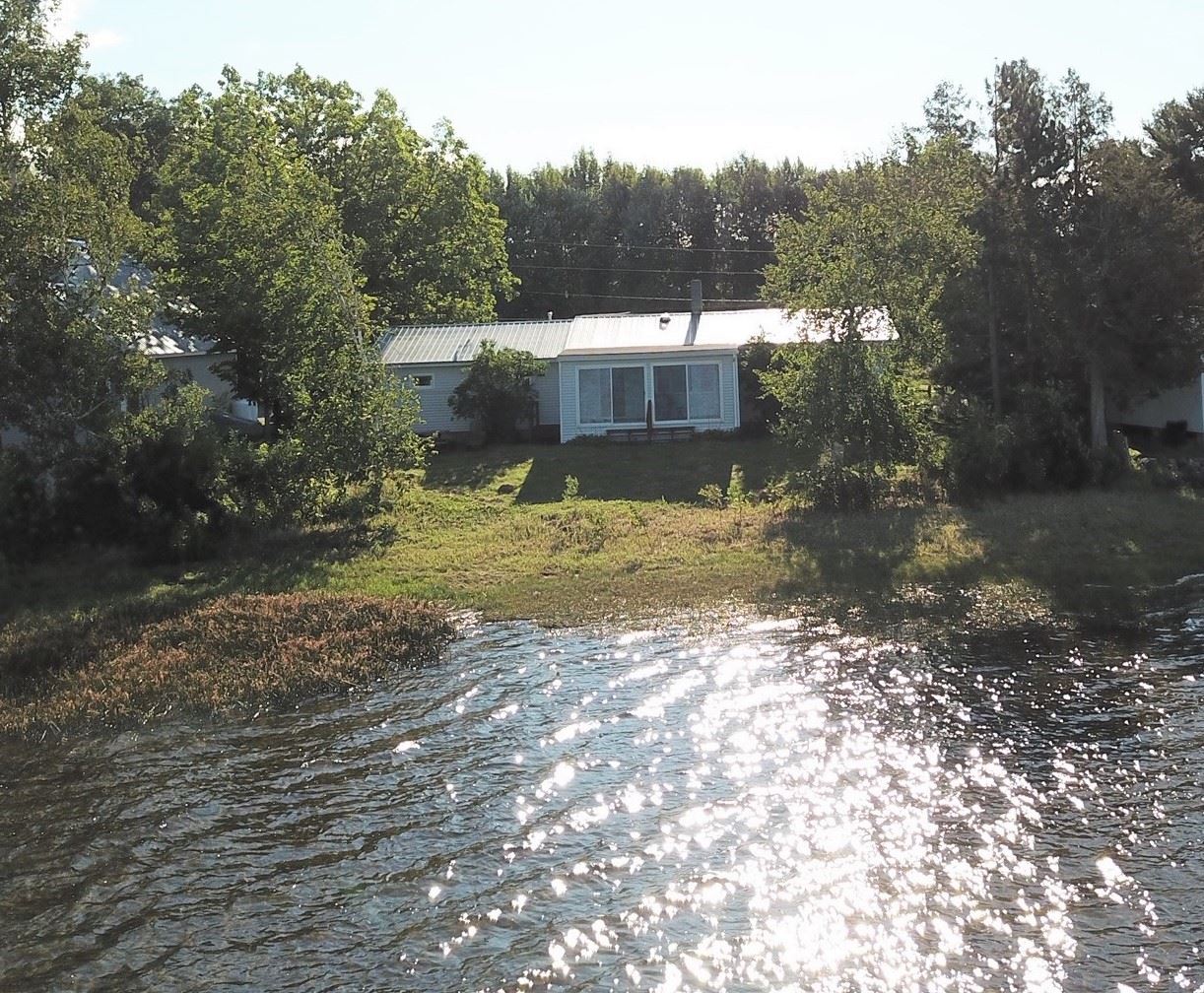 A white house sits on the shore of a lake