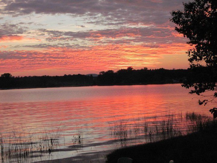 A sunset over a lake with trees in the foreground