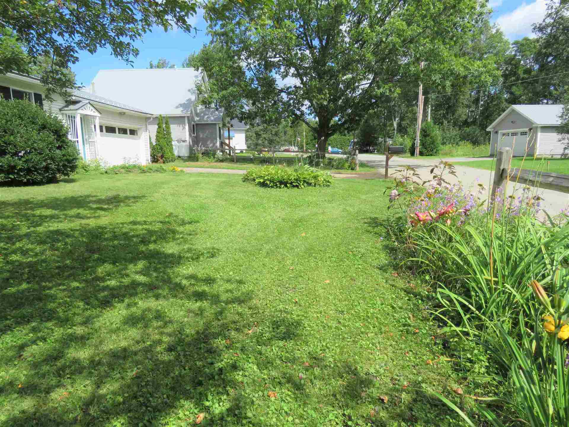 A lush green yard with a white house in the background