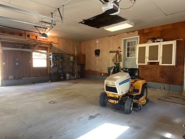 A yellow and white lawn mower is parked in a garage