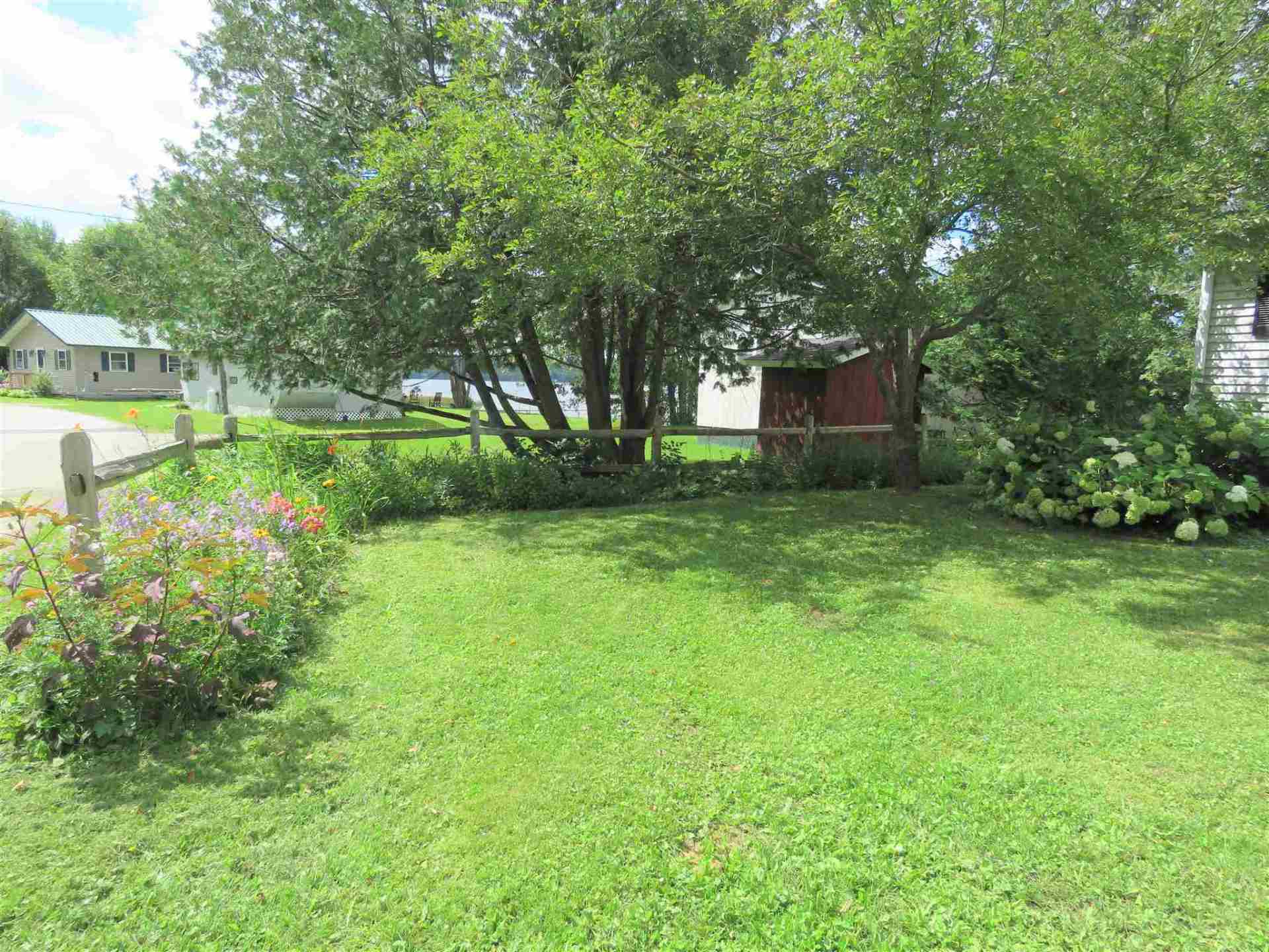 A lush green yard with trees and flowers in front of a house