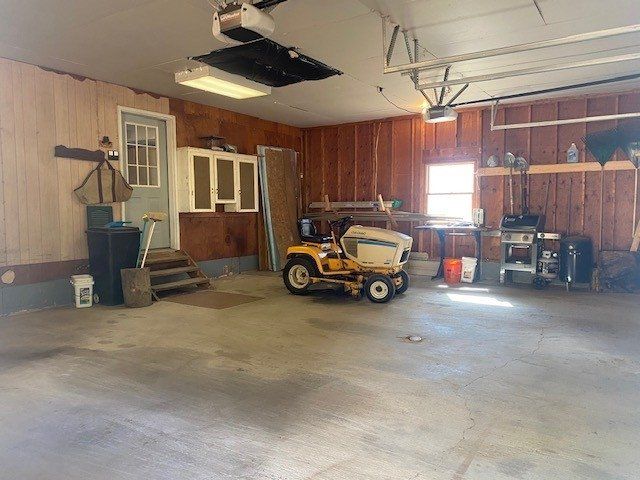 A yellow lawn mower is parked in a garage.
