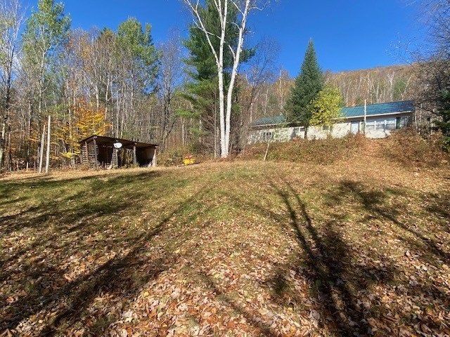 A house is sitting on top of a hill in the middle of a field surrounded by trees.