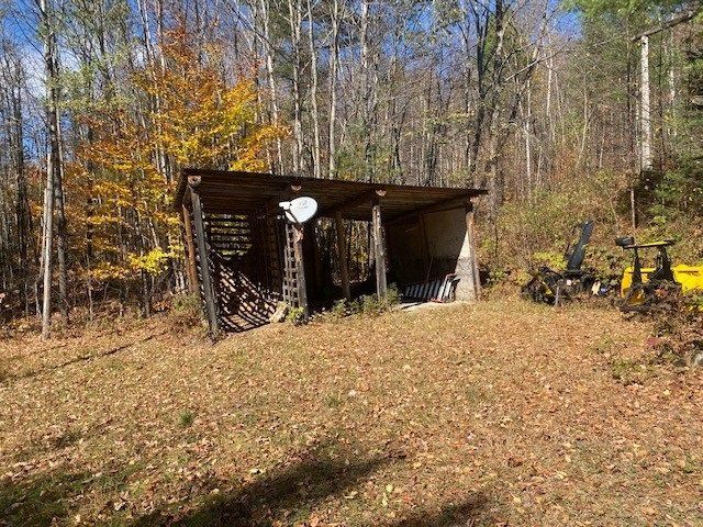 A shed in the middle of a field with trees in the background.