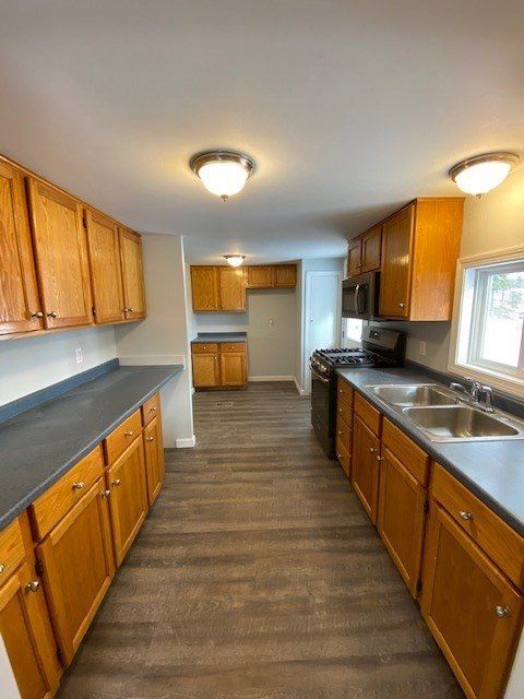 A kitchen with wooden cabinets, dark countertops, and stainless steel appliances.
