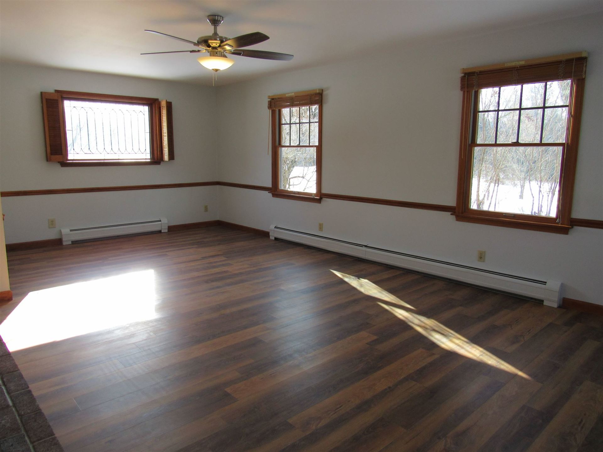 An empty room with a ceiling fan and two windows