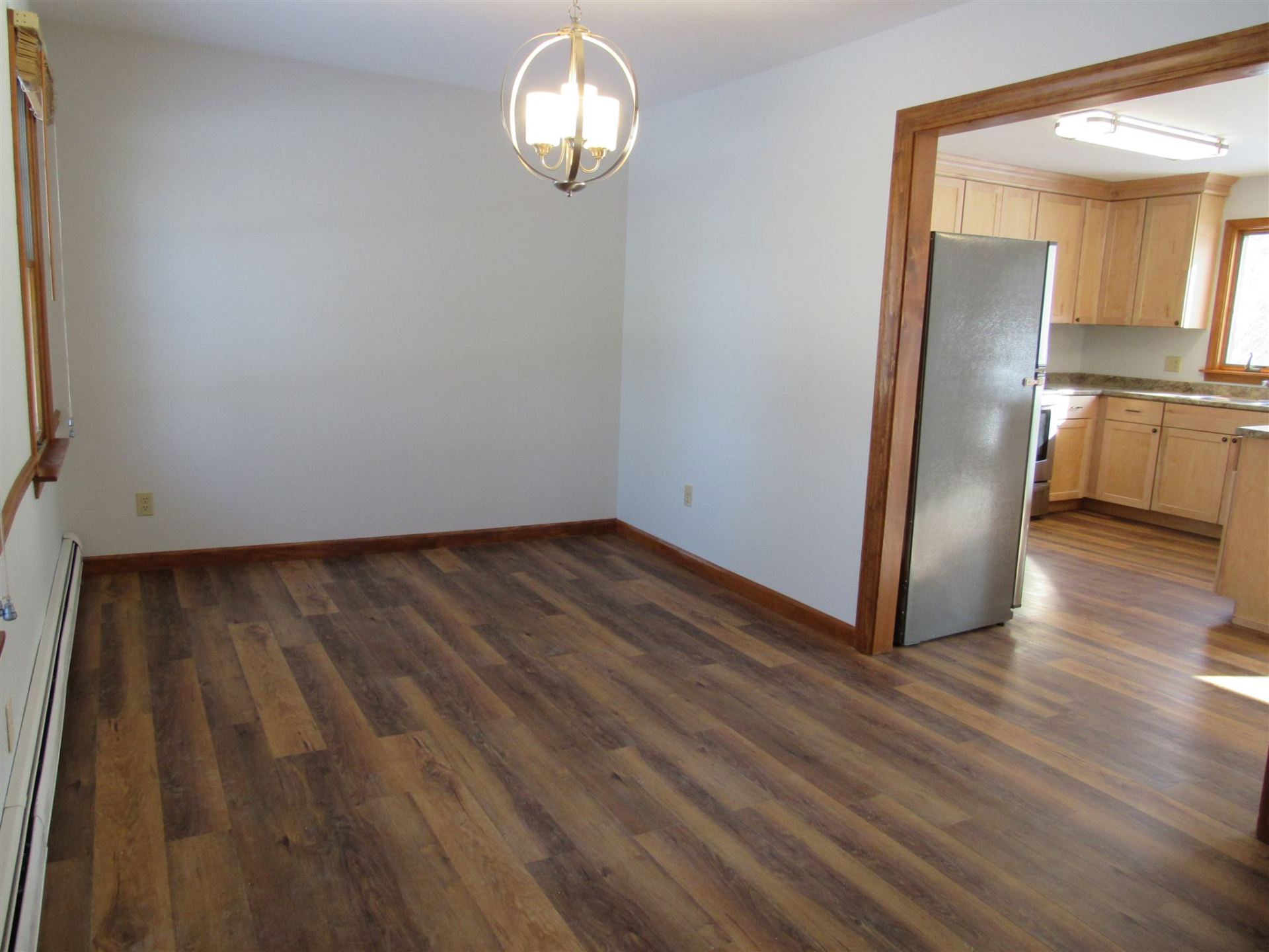 An empty room with hardwood floors and a chandelier