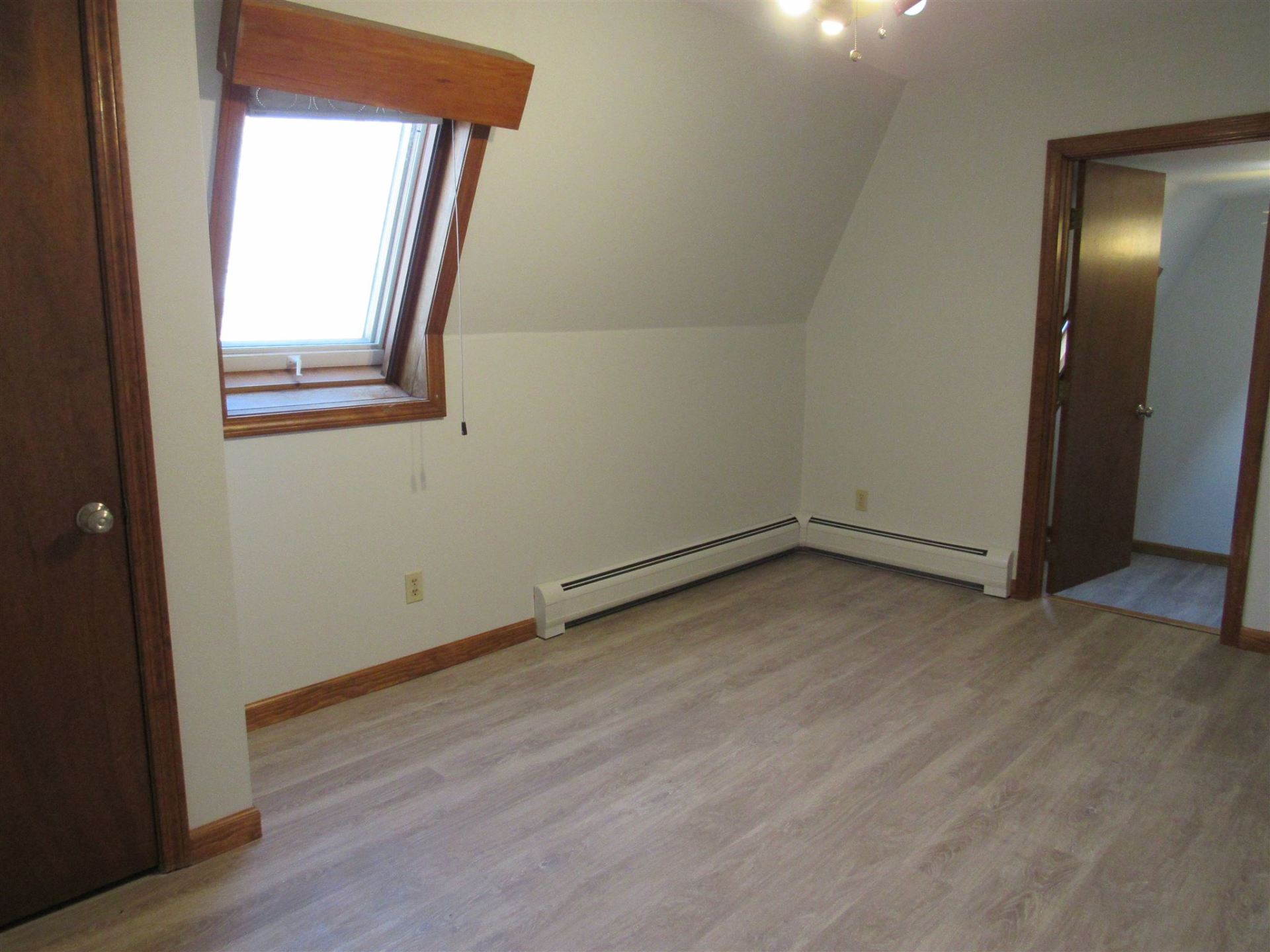 An empty room with hardwood floors and a window