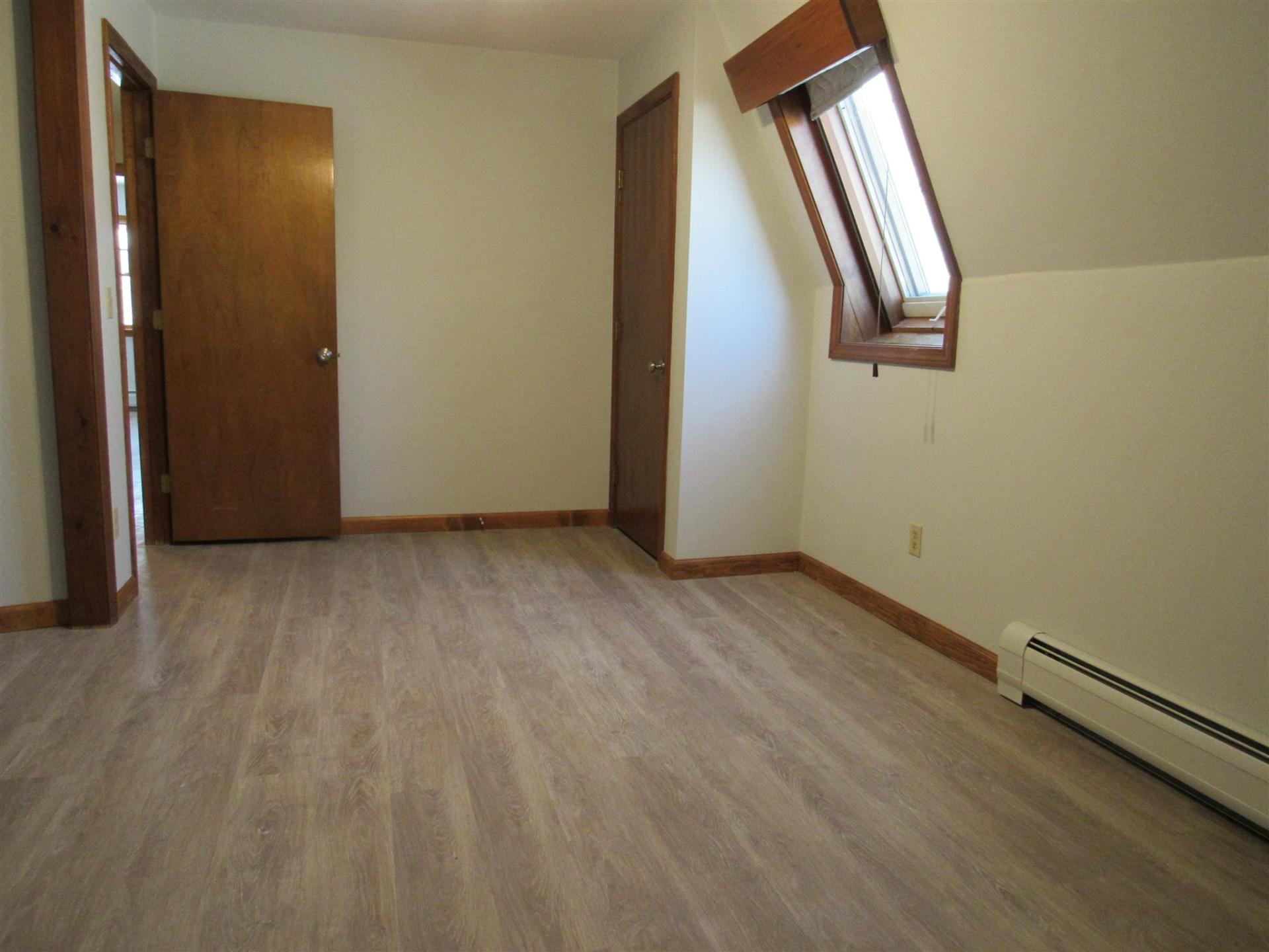 An empty room with hardwood floors and a window