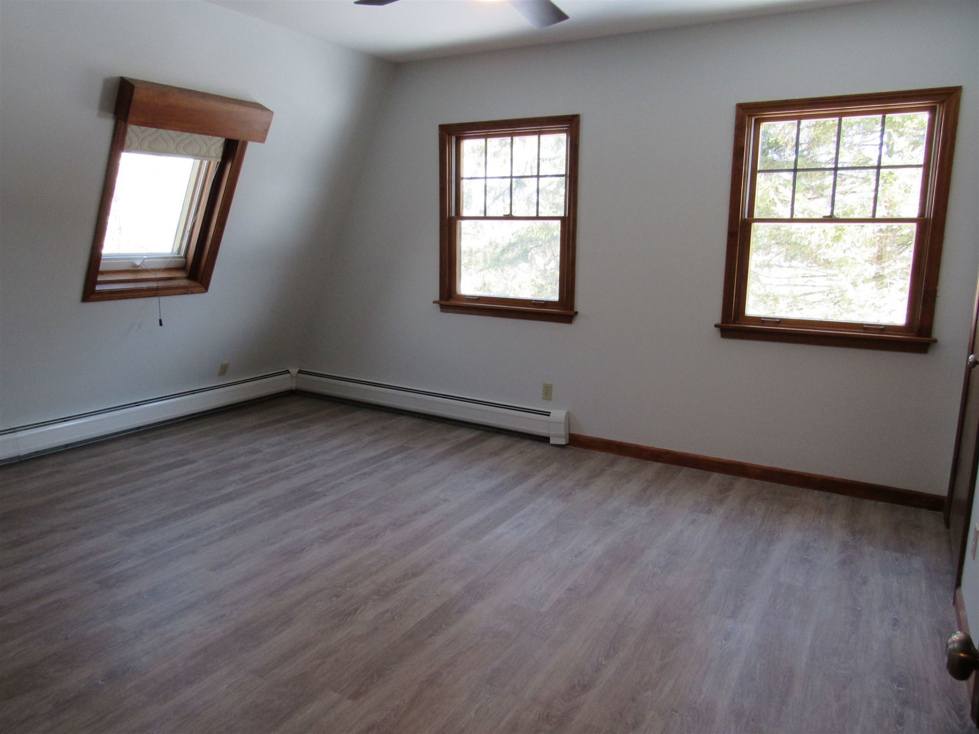 An empty room with two windows and a ceiling fan
