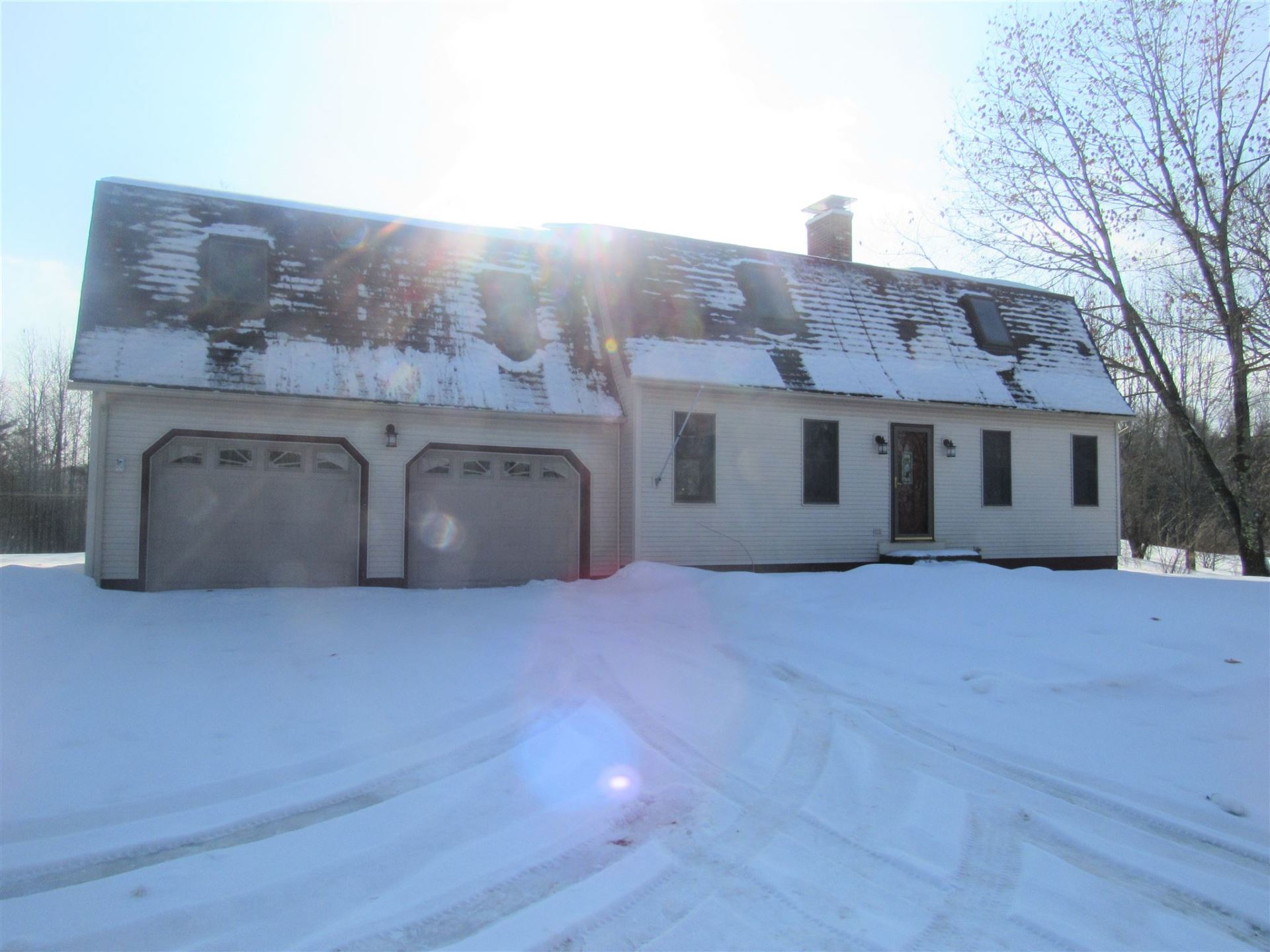 A white house with two garage doors is covered in snow