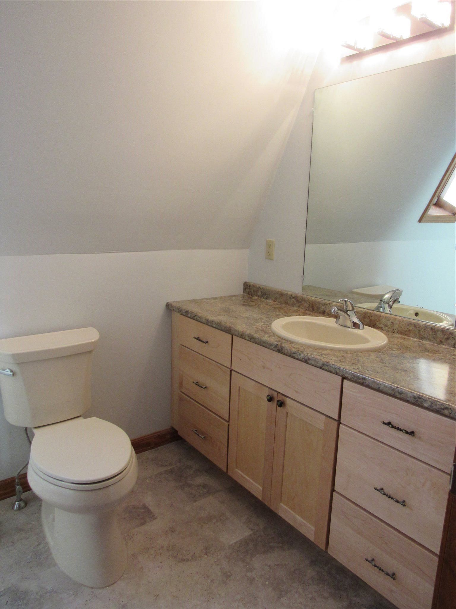 A bathroom with a toilet a sink and a mirror