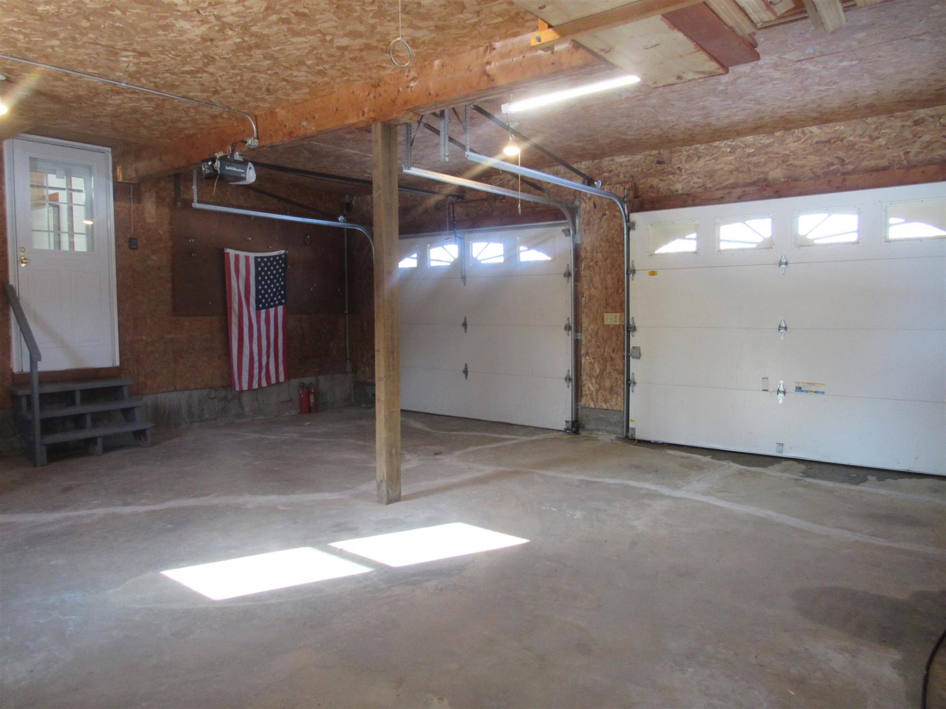 Garage interior with two closed white garage doors, an American flag, and a single entry door.