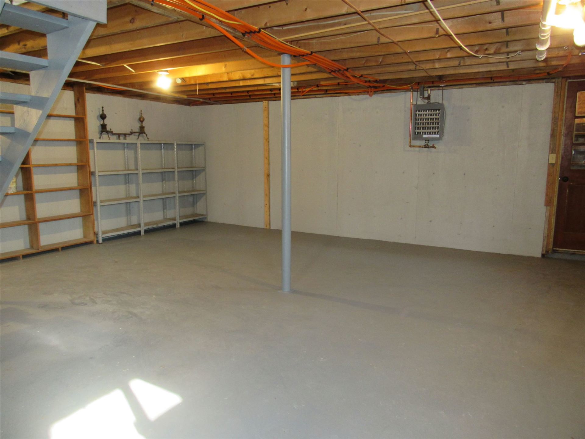 An empty basement with shelves and a staircase
