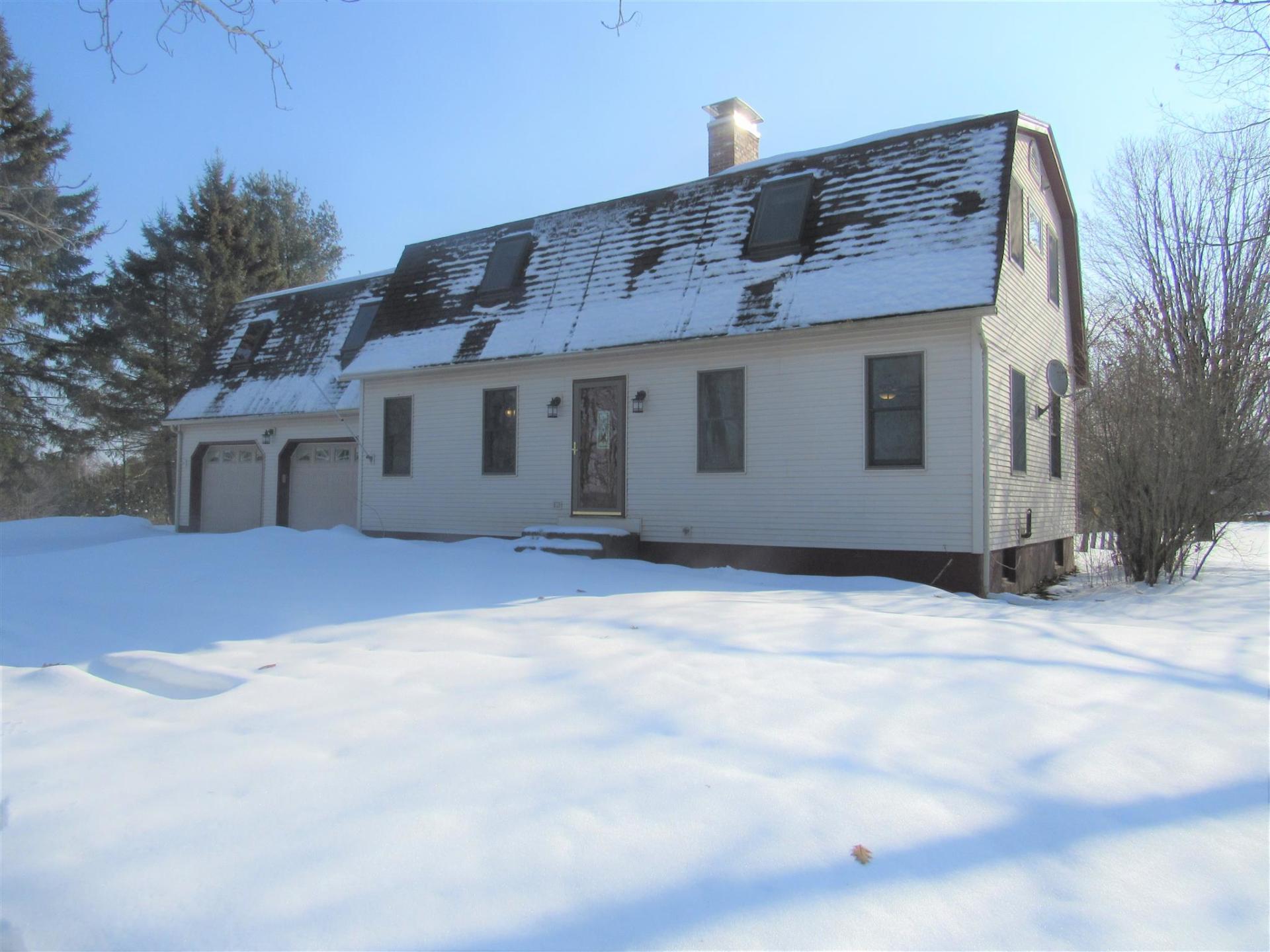 A snowy house with a garage and a chimney