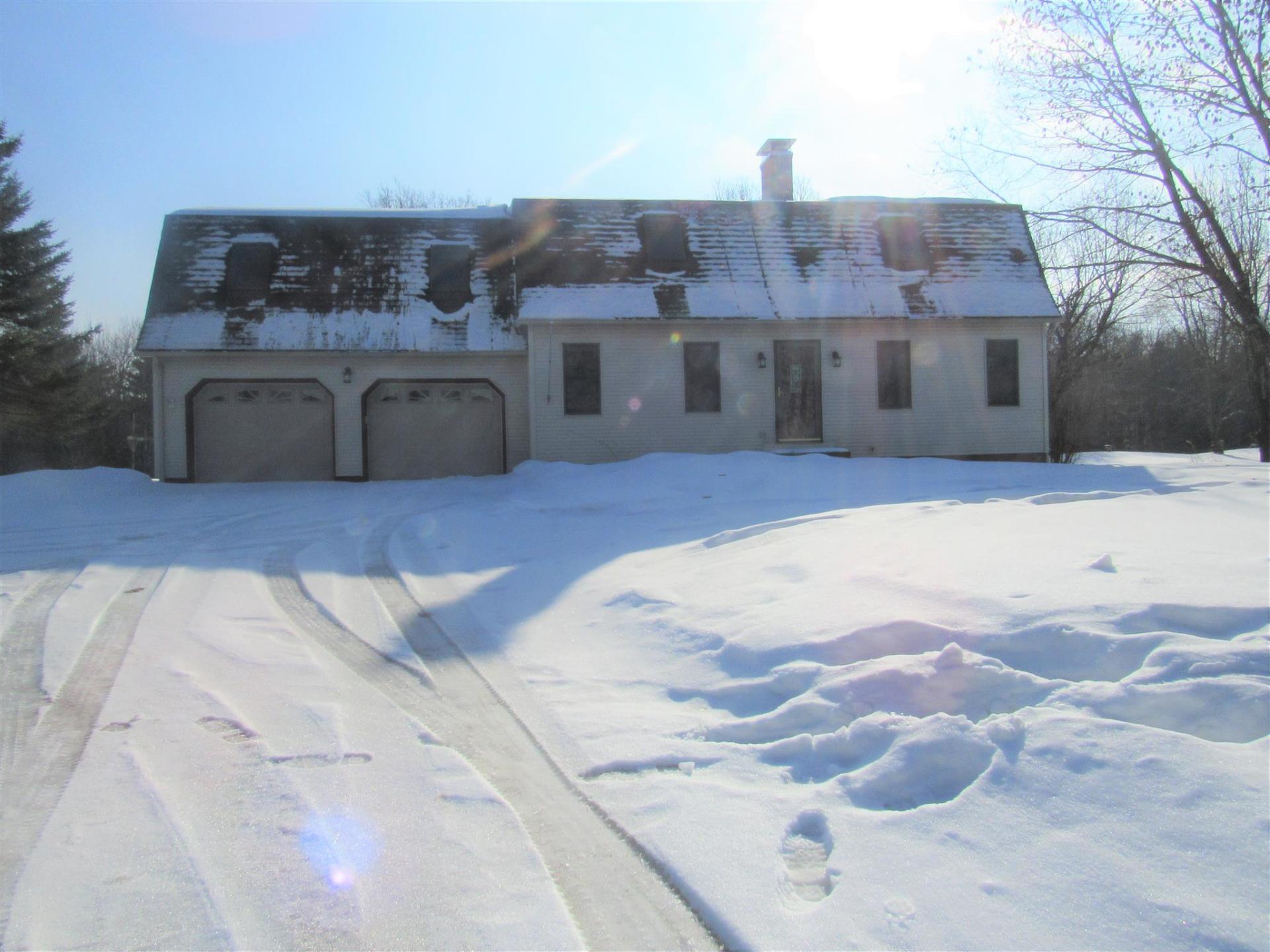 A snowy driveway leading to a house with two garage doors