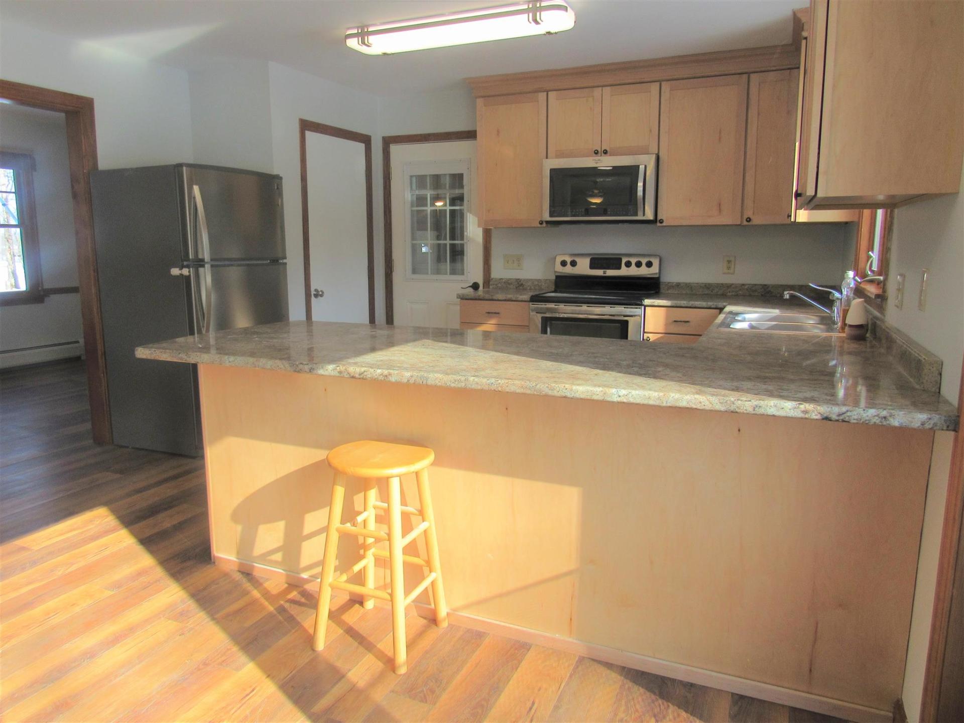 A kitchen with granite counter tops and a stainless steel refrigerator