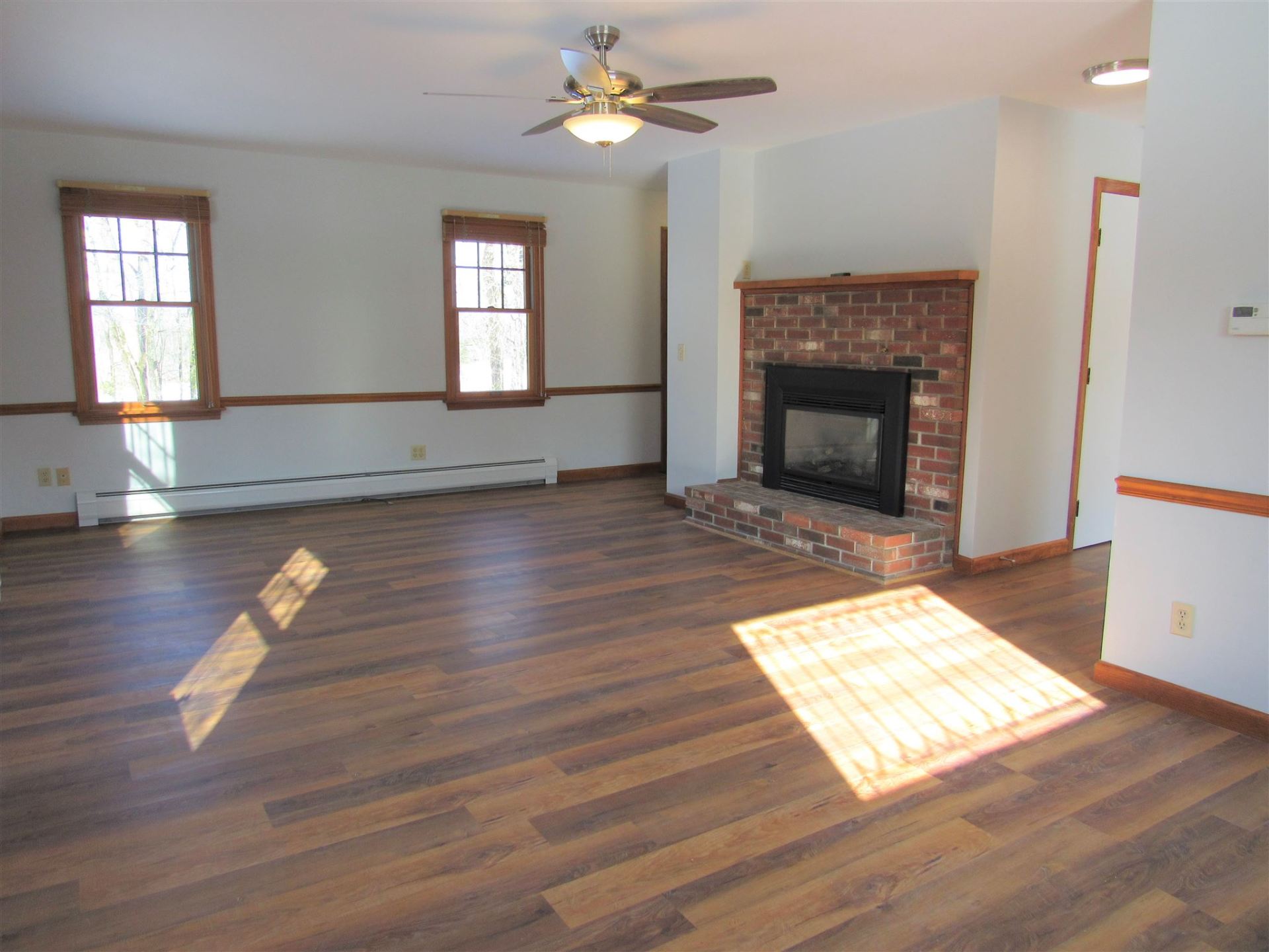 A living room with a fireplace and a ceiling fan