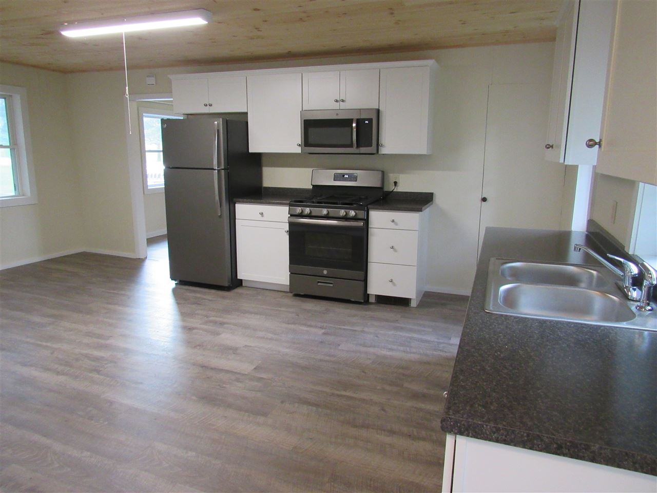 Kitchen with white cabinets, stainless steel appliances, and wood-look flooring.