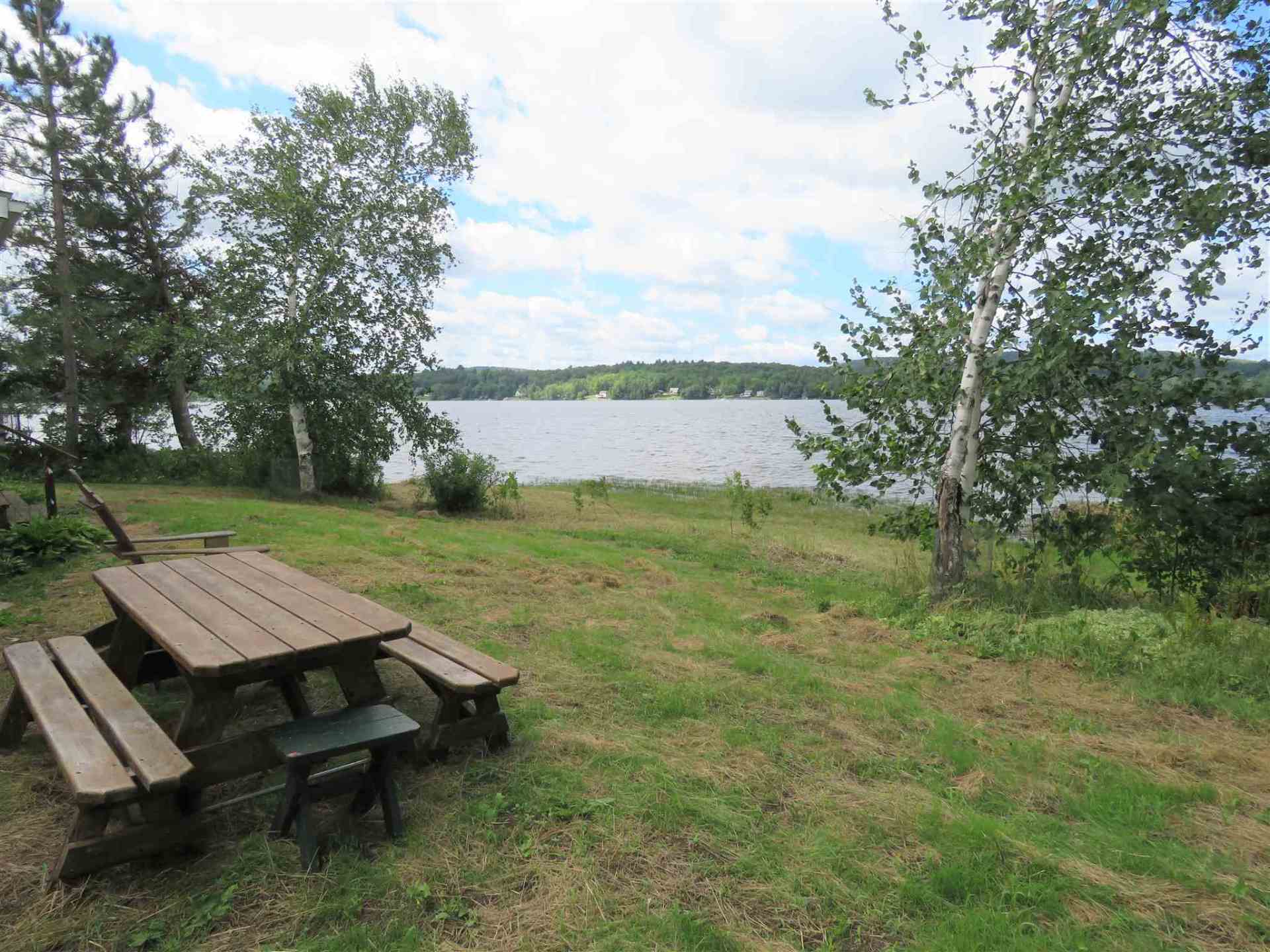 A picnic table sits in the grass near a lake